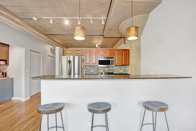 a kitchen with stainless steel appliances granite countertop a sink a stove cabinets and chairs