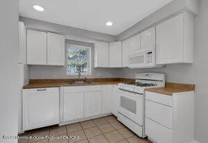 a kitchen with granite countertop white cabinets white stainless steel appliances and sink