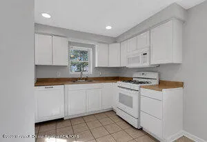 a kitchen with granite countertop white cabinets and white appliances