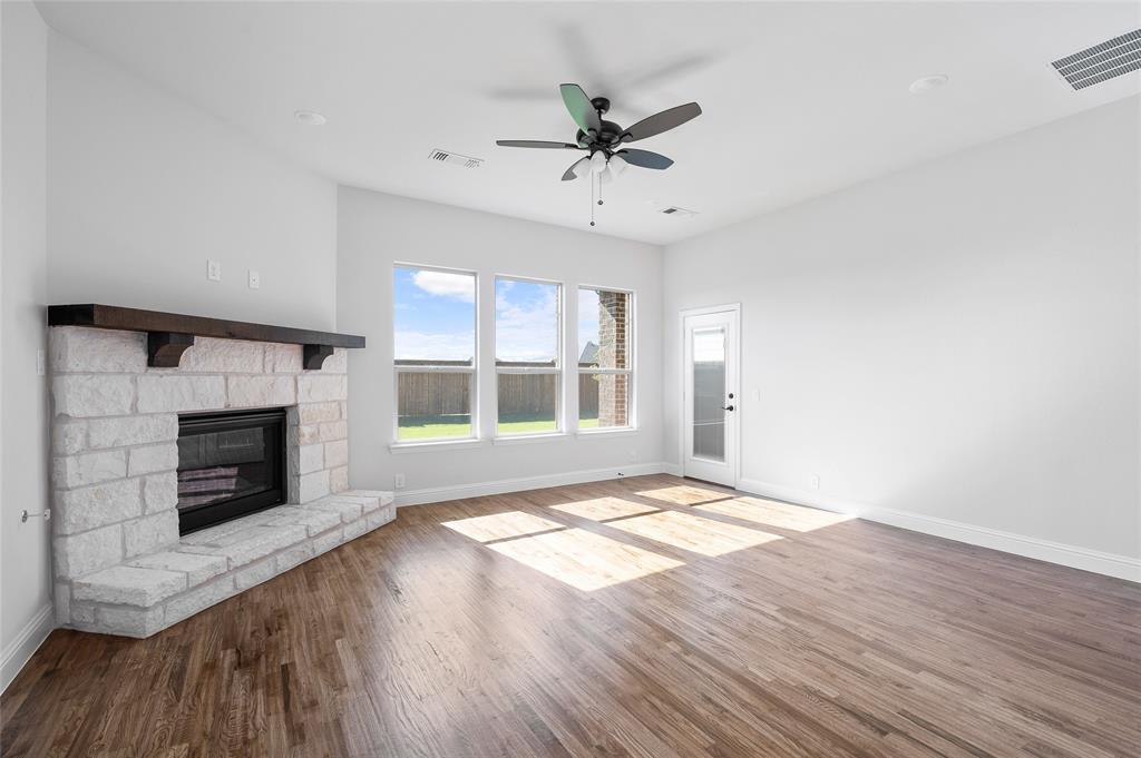 613 Brazos Drive Van Alstyne, TX 75495 - Photo 12 of 29 Unfurnished living room featuring wood finished floors, a fireplace, and a ceiling fan