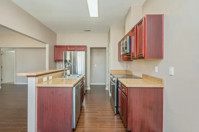 a kitchen with a sink stove top oven and wooden floor