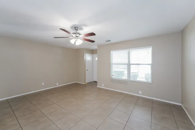 an empty room with chandelier fan and windows