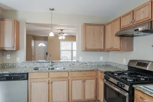 a kitchen with granite countertop a sink a stove and cabinets