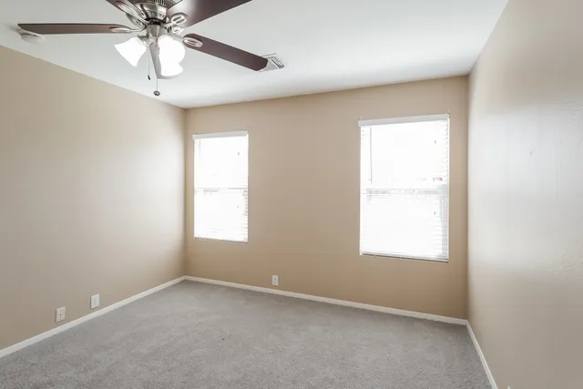 an empty room with a window and a fan