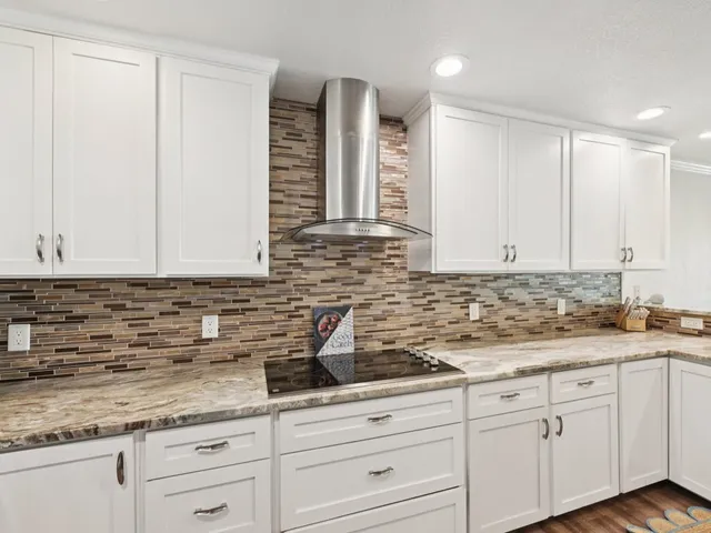 a kitchen with granite countertop white cabinets and a sink