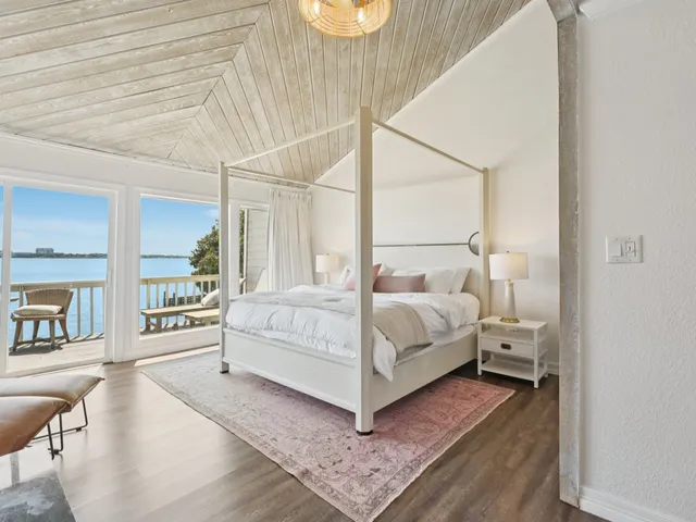 a bedroom with a white bed and white walls with the wooden floor