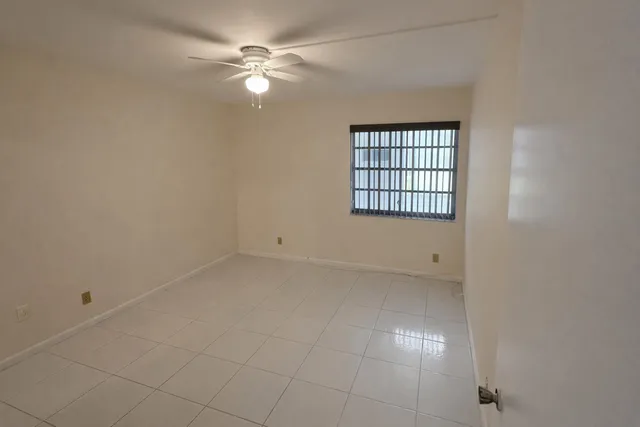 an empty room with chandelier fan and windows