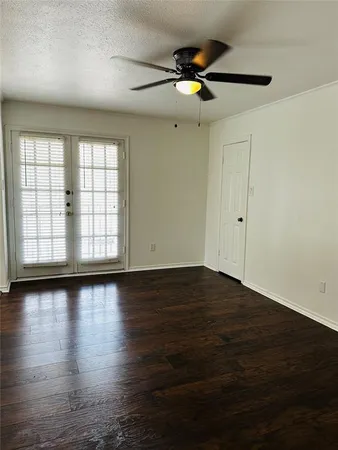 an empty room with wooden floor fan and windows