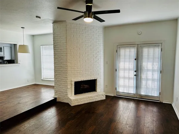 a view of a livingroom with wooden floor a ceiling fan and a fireplace