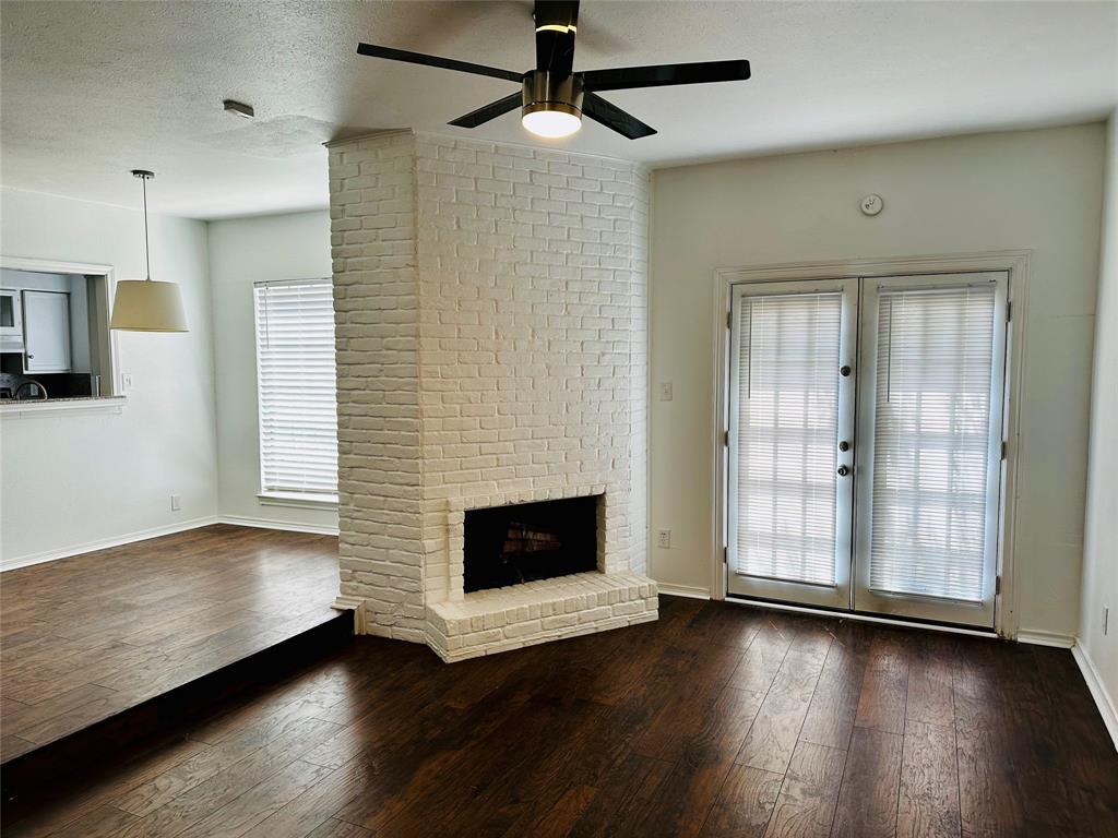 4000 Rawlins Street, Unit 101B Dallas, TX 75219 - Photo 3 of 27 a view of a livingroom with wooden floor a ceiling fan and a fireplace