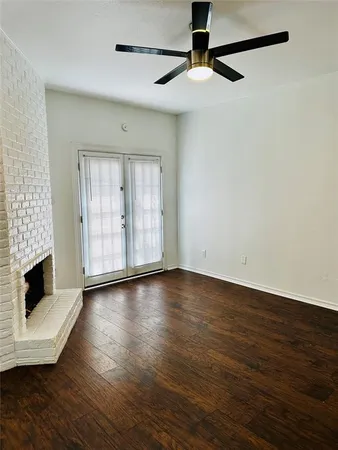 an empty room with wooden floor fireplace and windows