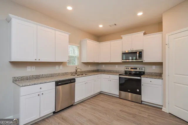 a kitchen with stainless steel appliances granite countertop a stove a sink and white cabinets