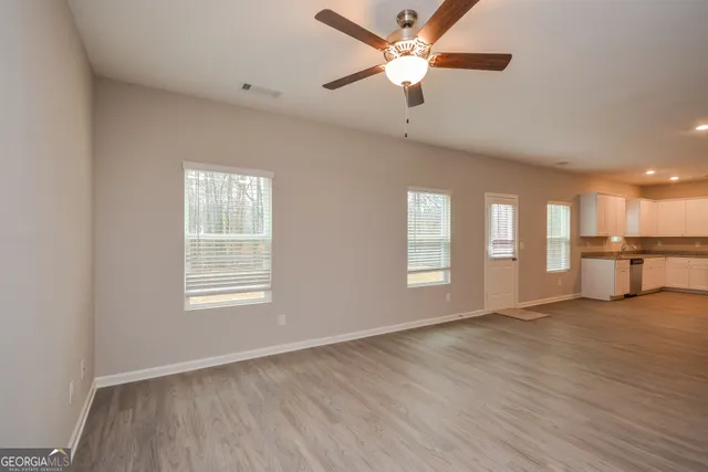 a view of an empty room with window and wooden floor
