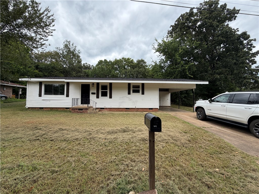 909 Riddell Street Clarksville, AR 72830 - Photo 1 of 26 White siding exterior featuring black window shutters and a black front door