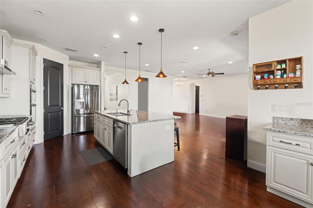 4387 Harborpointe Drive Port Richey, FL 34668 - Photo 11 of 46 a kitchen with stainless steel appliances granite countertop a refrigerator a stove and a wooden floors