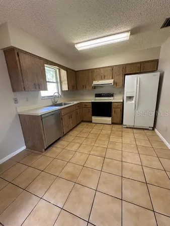 a kitchen with stainless steel appliances granite countertop a stove a sink and a refrigerator