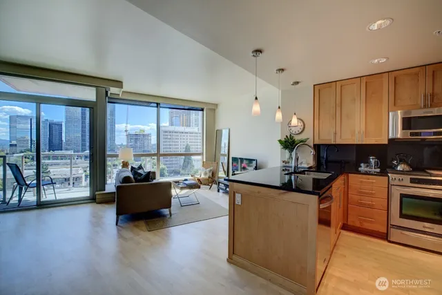 a living room with stainless steel appliances furniture cabinets and a wooden floor