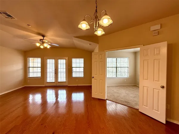 a view of an empty room with window and wooden floor