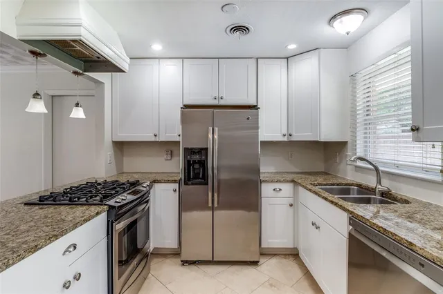 a kitchen with granite countertop kitchen island stainless steel appliances a stove a sink a refrigerator and cabinets