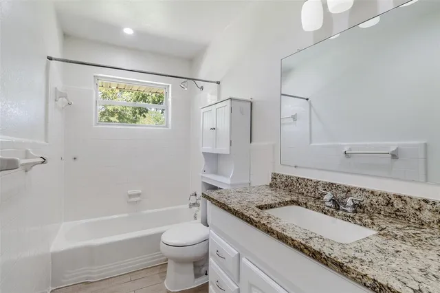 a bathroom with a granite countertop sink and a bathtub