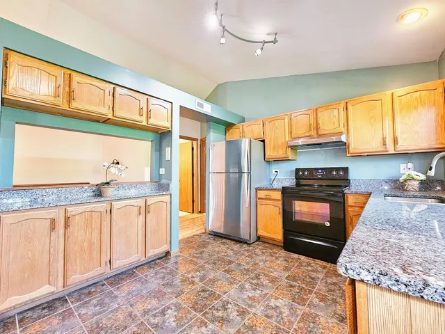 a kitchen with stainless steel appliances granite countertop a stove a sink and a refrigerator