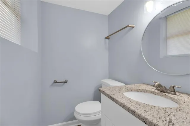 a bathroom with a granite countertop toilet sink mirror and vanity