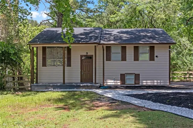 a view of house with garden and tall trees