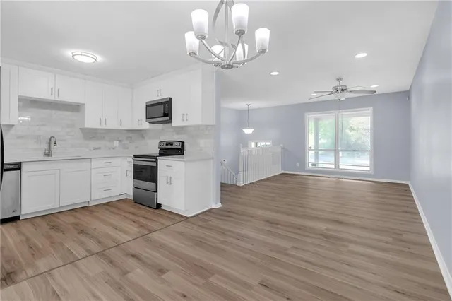 a kitchen with stainless steel appliances granite countertop a stove top oven a sink cabinets and wooden floor