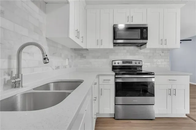 a kitchen with sink a microwave and cabinets