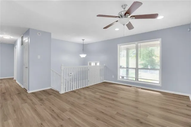 a view of an empty room with a window and wooden floor