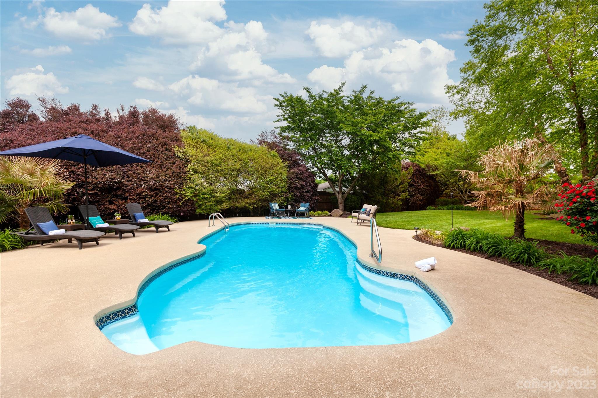 a view of a swimming pool with a yard and sitting area