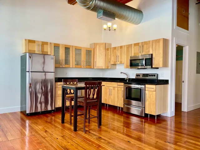a kitchen with granite countertop wooden floors stainless steel appliances and dining table
