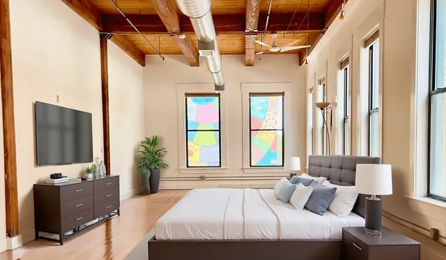 a bedroom with a large bed and a flat tv screen on dresser