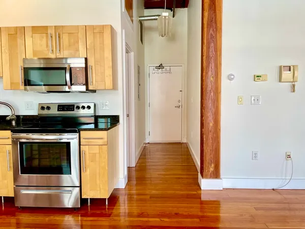 a view of a kitchen with stainless steel appliances wooden floor and cabinets