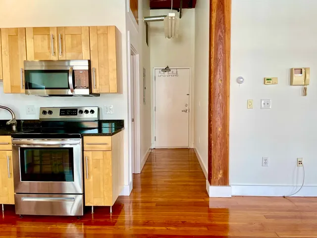 a view of a kitchen with stainless steel appliances wooden floor and cabinets