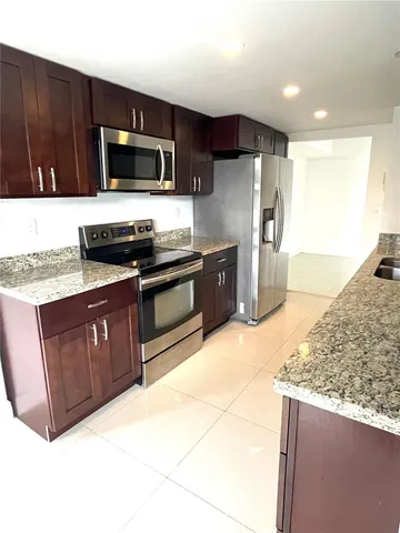 a kitchen with stainless steel appliances granite countertop a stove a sink and a microwave