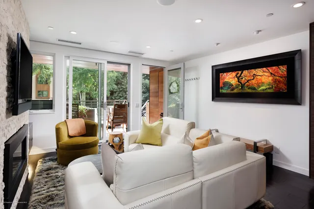 a living room with furniture floor to ceiling window hardwood floor and a flat screen tv