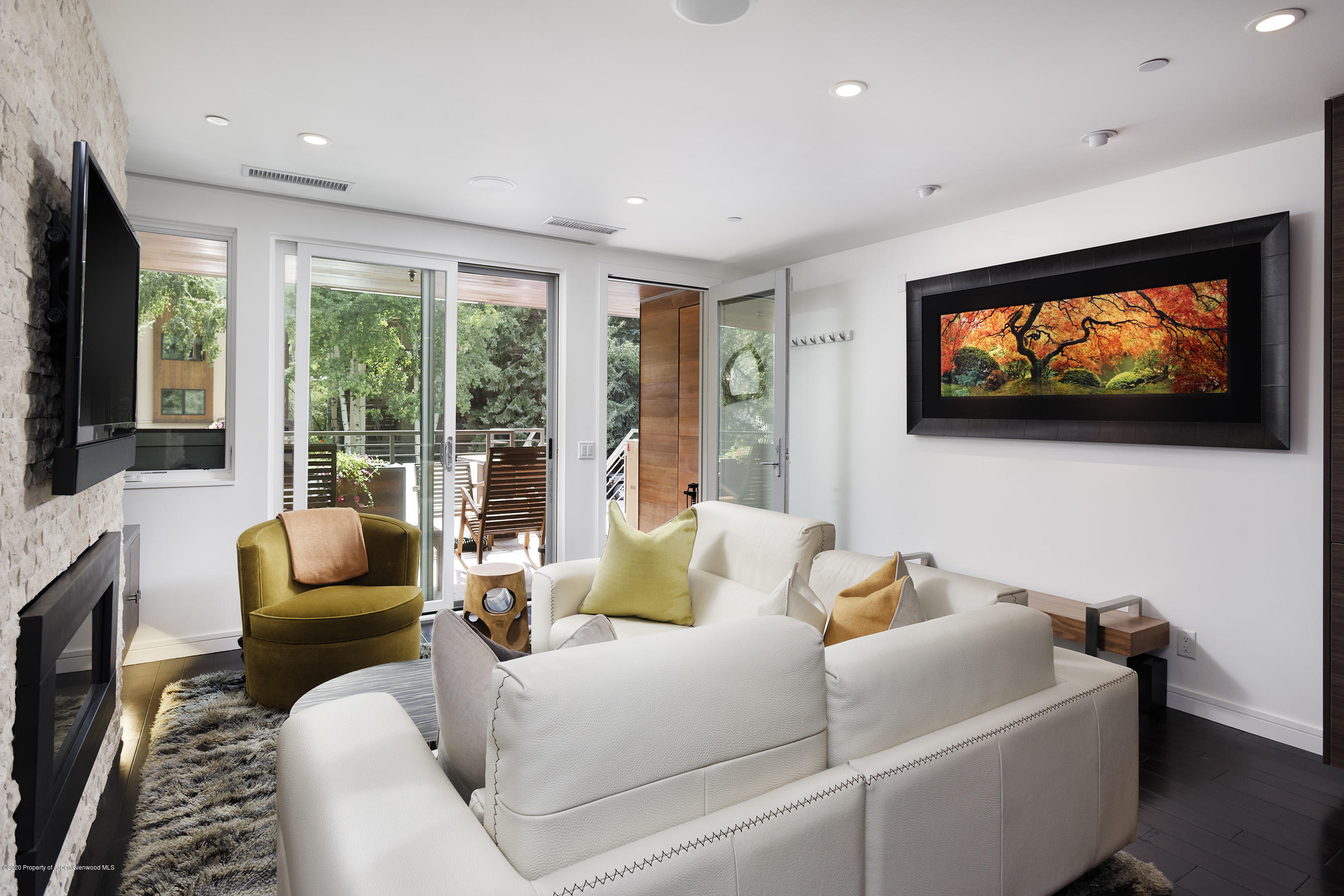 100 East Cooper Avenue, Unit 12 Aspen, CO 81611 - Photo 2 of 12 a living room with furniture floor to ceiling window hardwood floor and a flat screen tv
