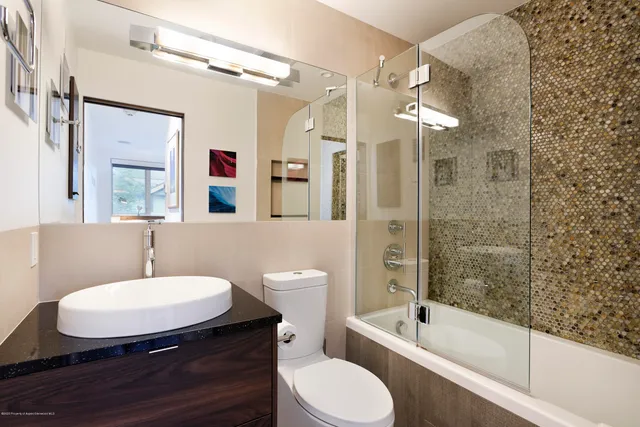 a bathroom with a sink a toilet a mirror a bathtub and shower