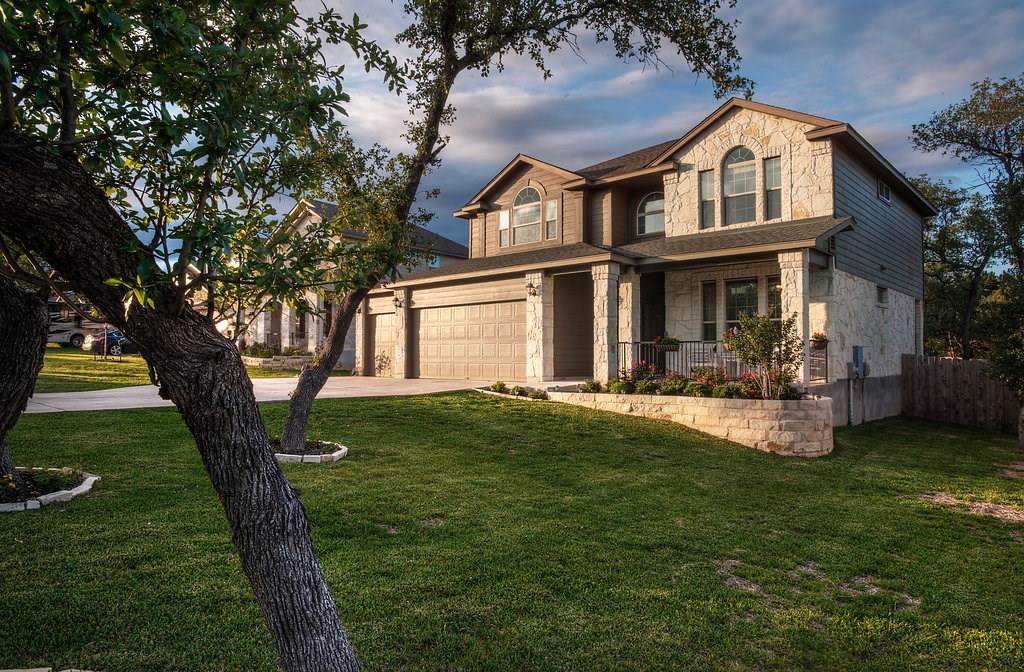 a front view of a house with garden and trees