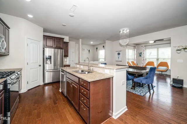 a kitchen with stainless steel appliances granite countertop a table chairs stove and refrigerator