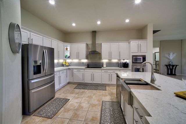 a kitchen with stainless steel appliances granite countertop a sink refrigerator and cabinets