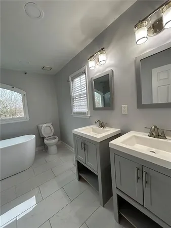 a spacious bathroom with a double vanity sink a mirror and a toilet