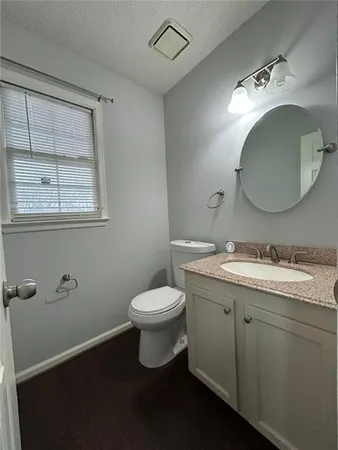 a bathroom with a granite countertop toilet sink mirror and vanity