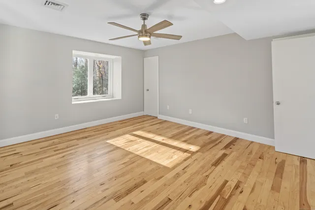 a view of an empty room with window and wooden floor