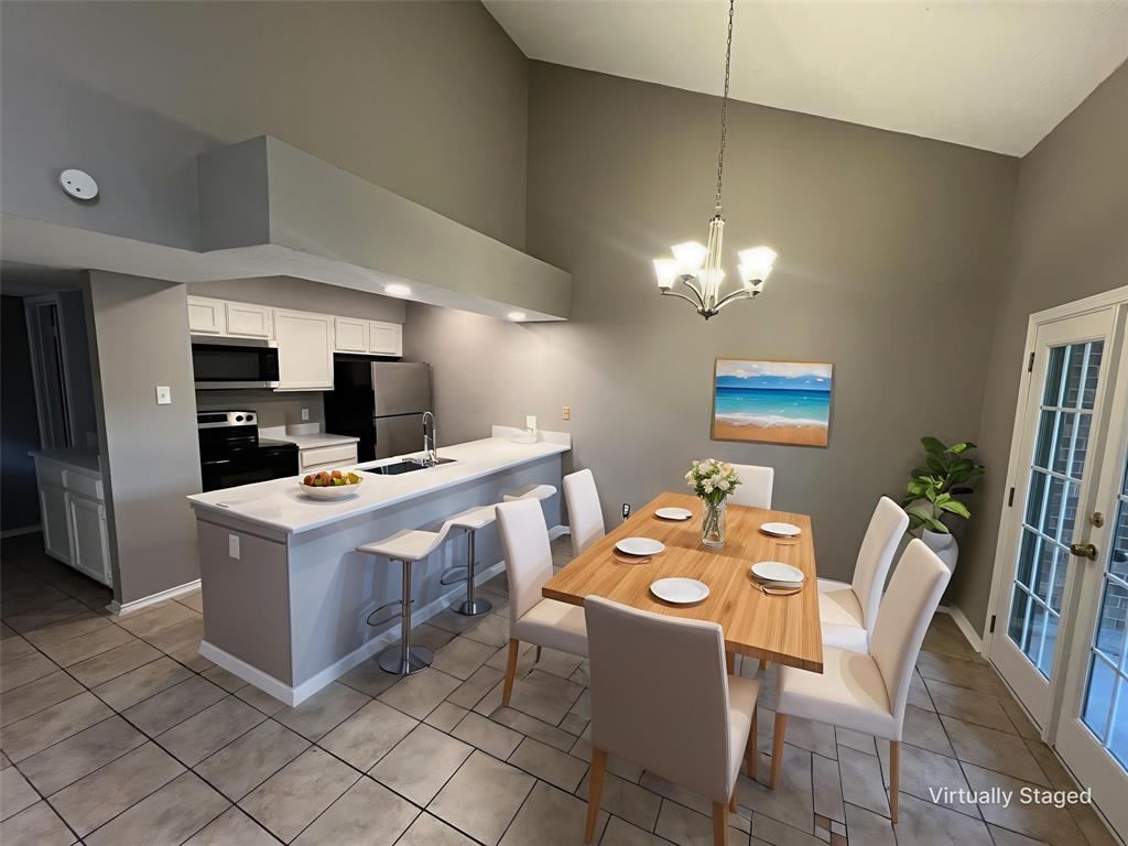 Dining room with high vaulted ceiling, a chandelier, and light tile patterned floors