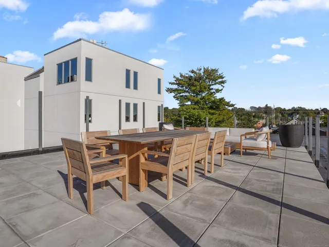 a patio with a table and chairs and potted plants
