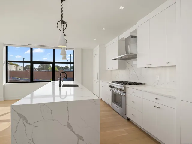 a kitchen with stainless steel appliances granite countertop a stove a sink and a refrigerator with white cabinets