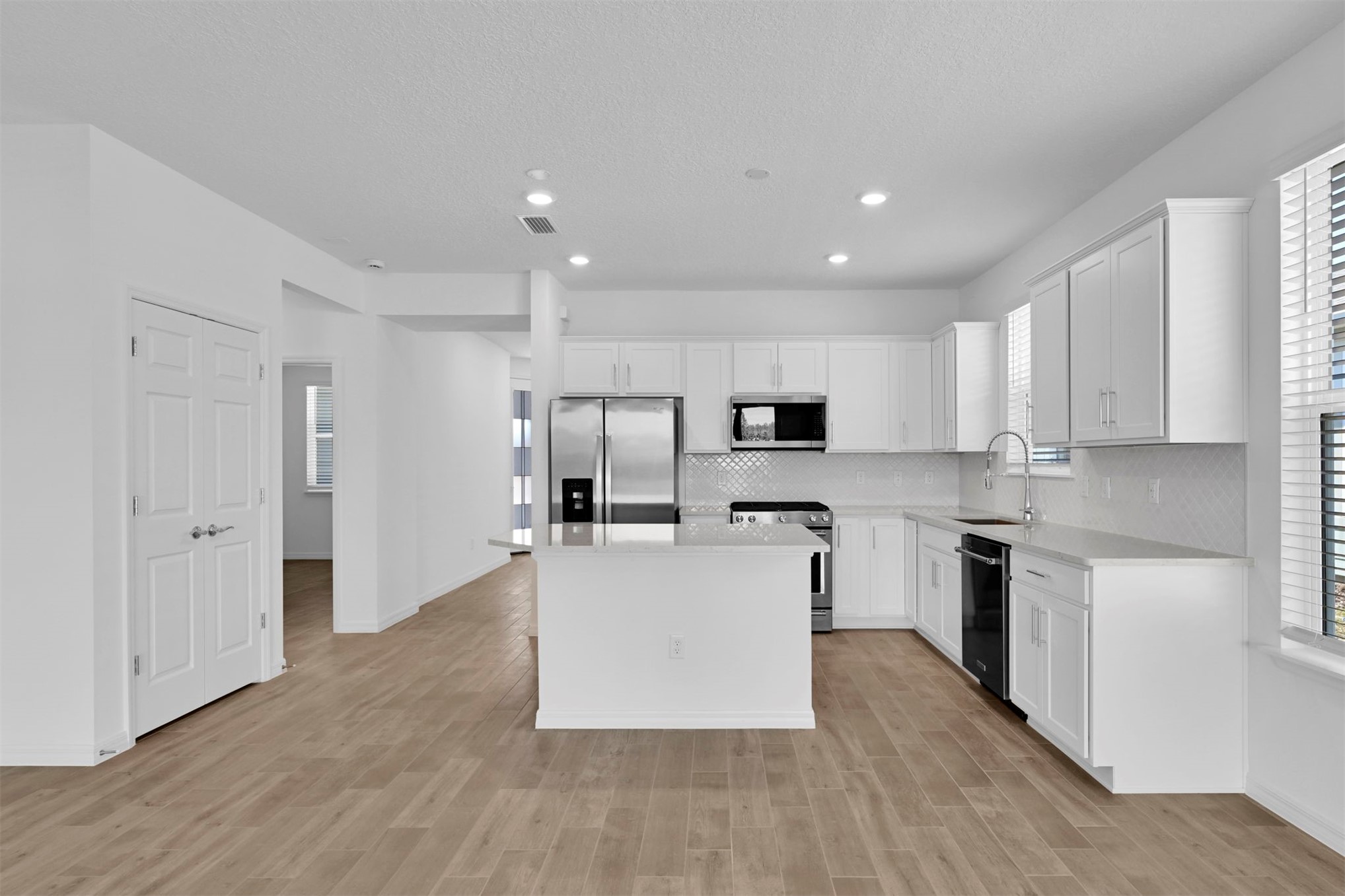 285 Ecliptic Loop Yulee, FL 32097 - Photo 6 of 42 a large kitchen with stainless steel appliances refrigerator a stove top oven and white cabinets with wooden floor