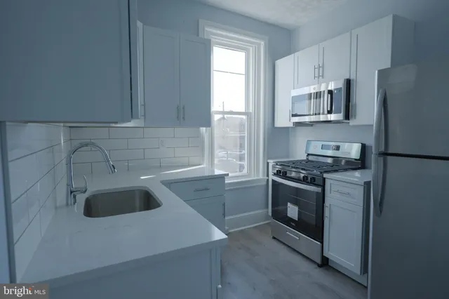 a kitchen with granite countertop a sink stove and refrigerator